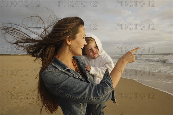 Mother holding baby at beach. Date : 2008
