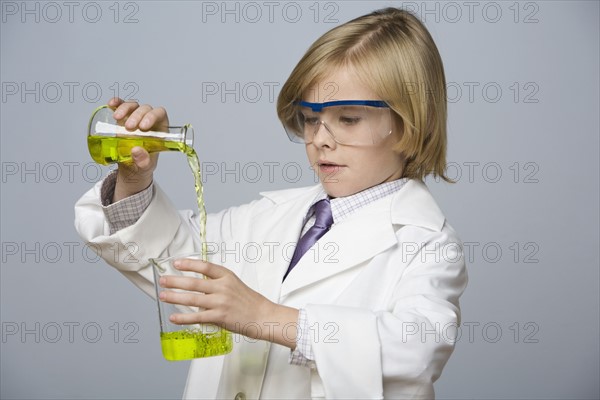 Boy pouring liquid into beaker. Date : 2008