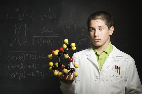Boy holding molecular model in front of blackboard . Date : 2008