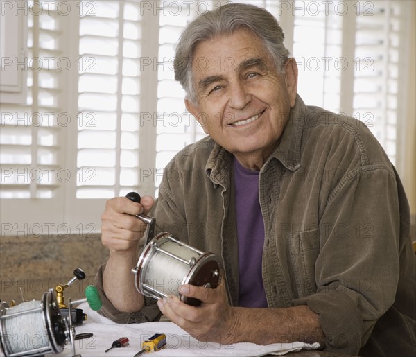 Senior man holding fishing reel. Date : 2008