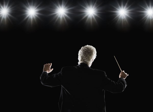 Man in tuxedo conducting under lights. Date : 2008