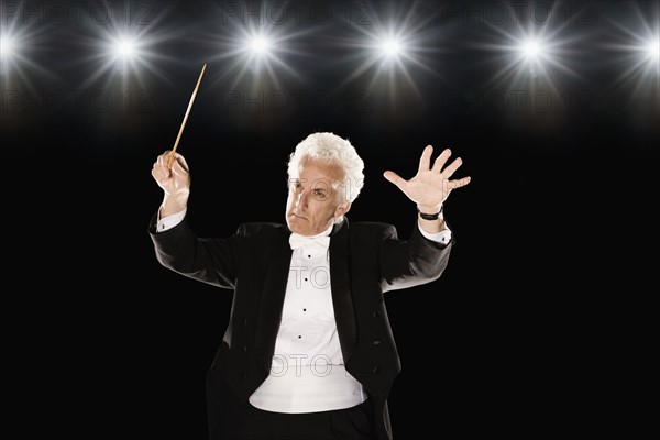 Man in tuxedo conducting under lights. Date : 2008