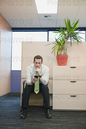 Businessman looking at cell phone. Date : 2008