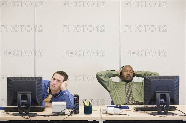 Multi-ethnic businessmen sitting at desks. Date : 2008