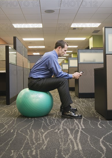 Businessman sitting on exercise ball. Date : 2008