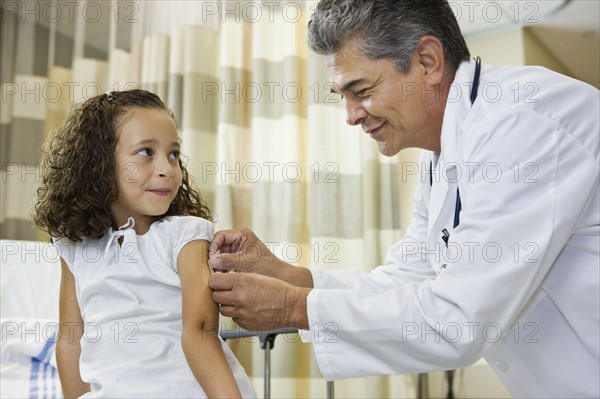 Male doctor bandaging girl’s arm. Date : 2008