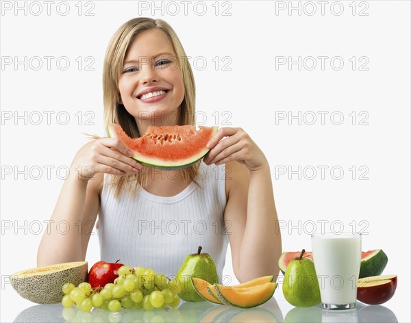 Woman with assorted fruit and glass of milk. Date : 2008
