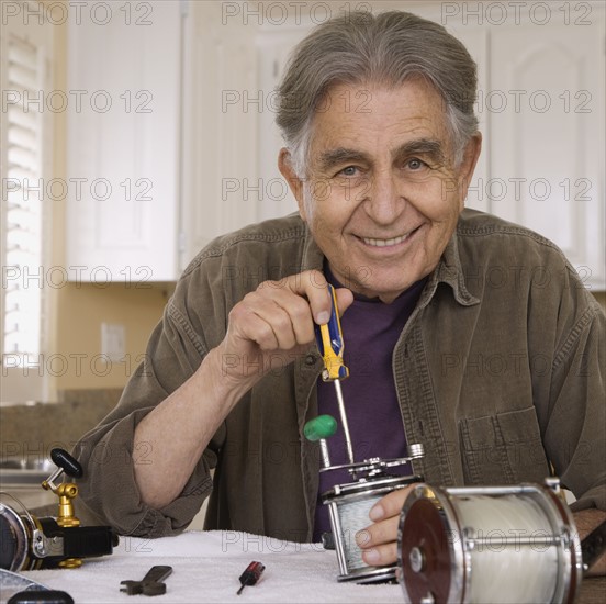 Senior man fixing fishing reel. Date : 2008