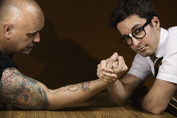 Nerdy man arm wrestling tattooed man. Date : 2008