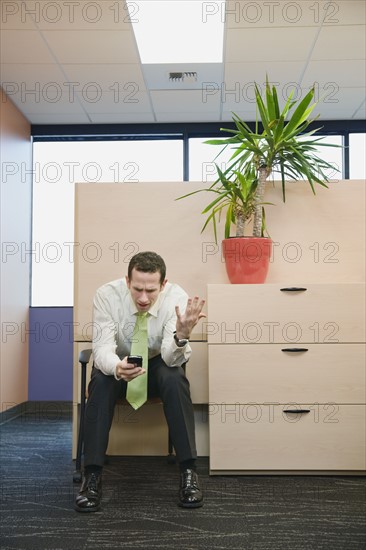 Frustrated businessman looking at cell phone. Date : 2008