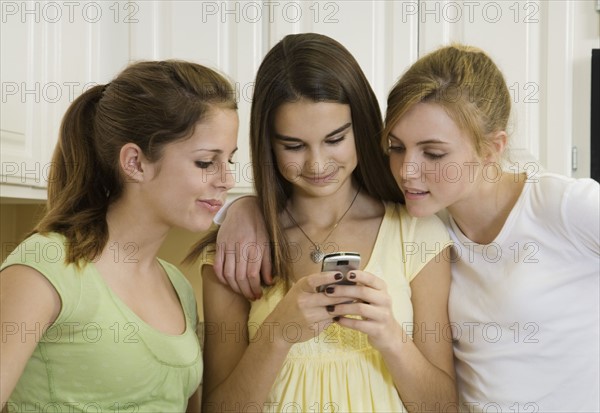 Teenaged girls looking at cell phone. Date : 2008