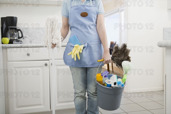 Woman holding mop and cleaning supplies. Date : 2008