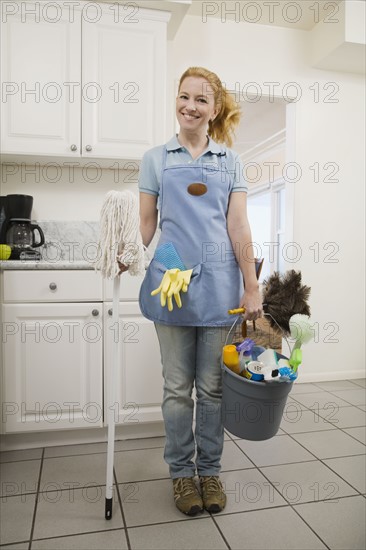 Woman holding mop and cleaning supplies. Date : 2008