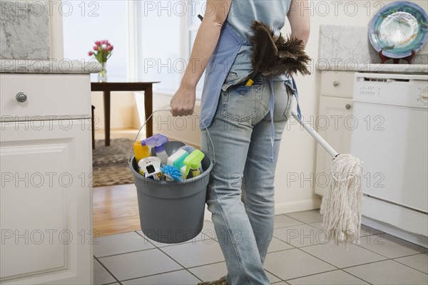 Woman holding mop and cleaning supplies. Date : 2008