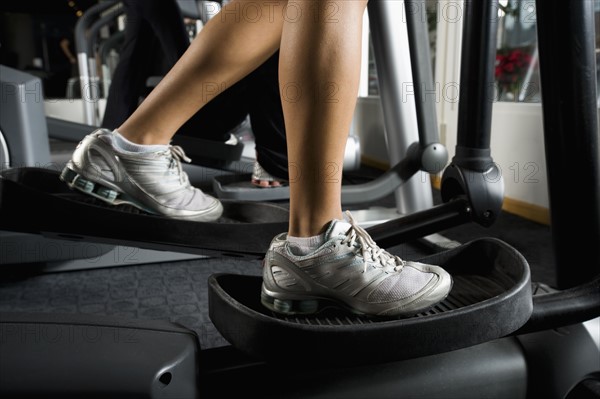 Woman exercising on elliptical machine. Date : 2008