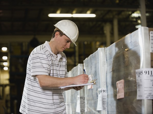 Warehouse worker writing on clipboard. Date : 2008