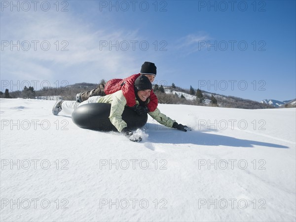 Mother and son riding on tube in snow. Date : 2008