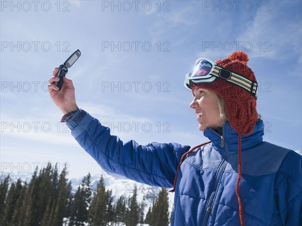 Woman in ski gear taking photograph. Date : 2008