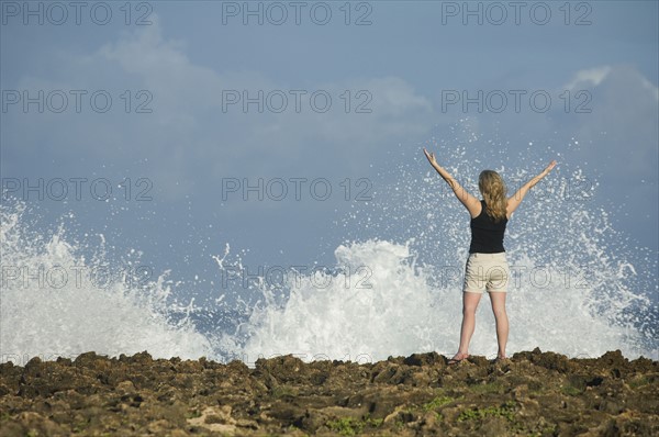 Woman with arms raised in front of ocean, Oahu, Hawaii, United States. Date : 2008