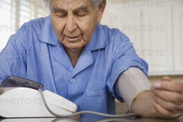 Senior man taking own blood pressure. Date : 2008