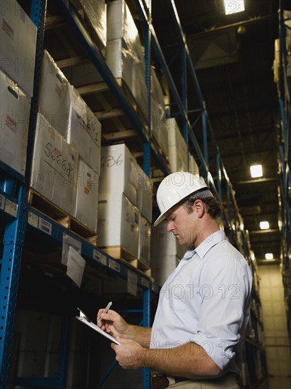 Warehouse worker writing on clipboard. Date : 2008