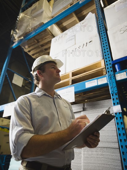 Warehouse worker writing on clipboard. Date : 2008