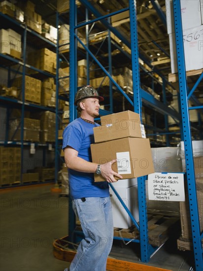 Warehouse worker carrying stack of boxes. Date : 2008