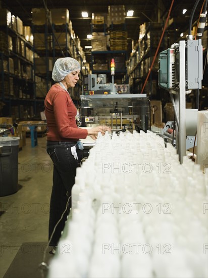 Hispanic female factory worker checking product. Date : 2008