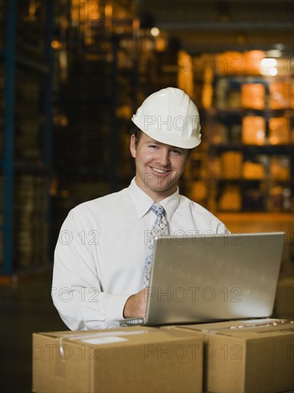 Businessman wearing hard hat in warehouse. Date : 2008