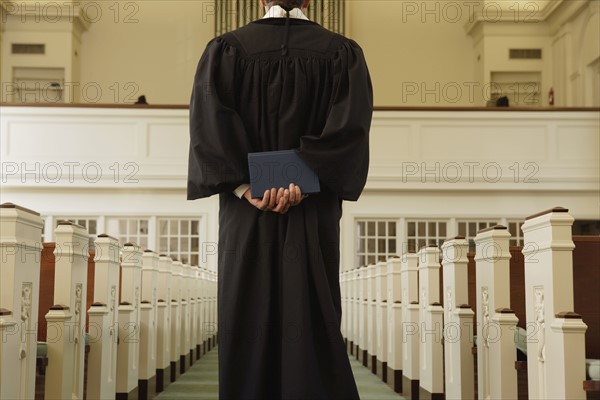 Priest holding bible behind back. Date : 2008