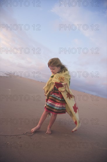 Girl drawing in sand with toe. Date : 2008