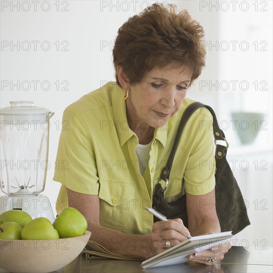 Senior woman writing list.