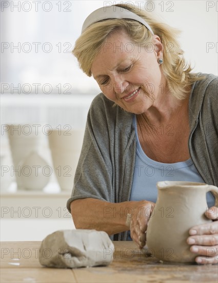 Senior woman making ceramic pot.