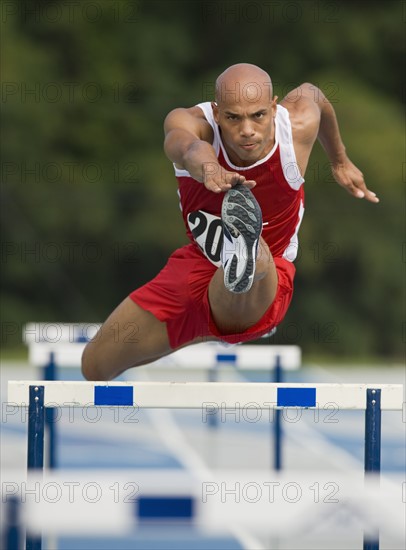 Runner jumping over hurdle.