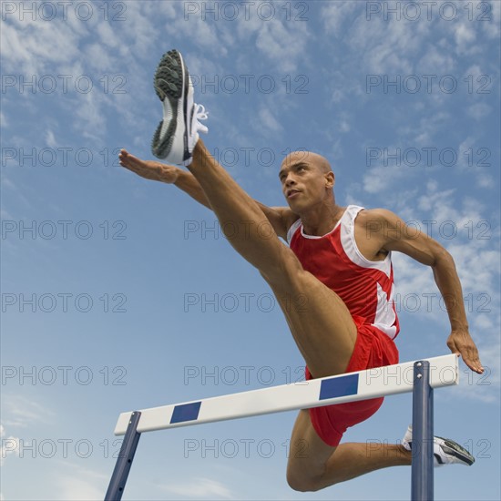 Runner jumping over hurdle.