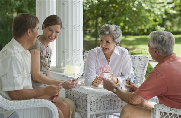 Couples playing card game on porch.