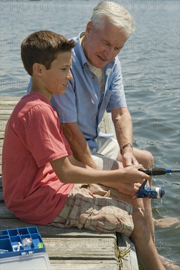 Grandfather and grandson fishing off dock.