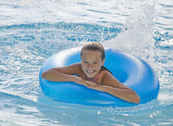 Girl playing with inflatable tube in swimming pool.