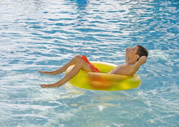 Boy relaxing in inflatable tube in swimming pool.