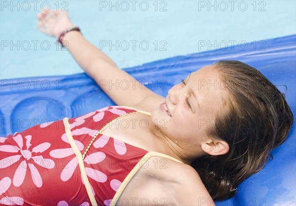 Girl playing on inflatable raft in swimming pool. Date : 2008