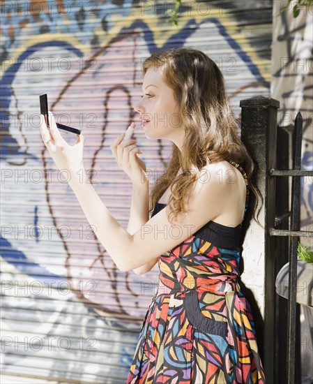 Young woman applying lipstick. Date : 2008