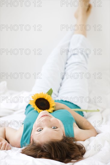 Teenage girl holding flower in bed. Date : 2008