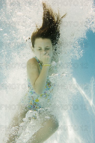 Girl plugging nose underwater. Date : 2008