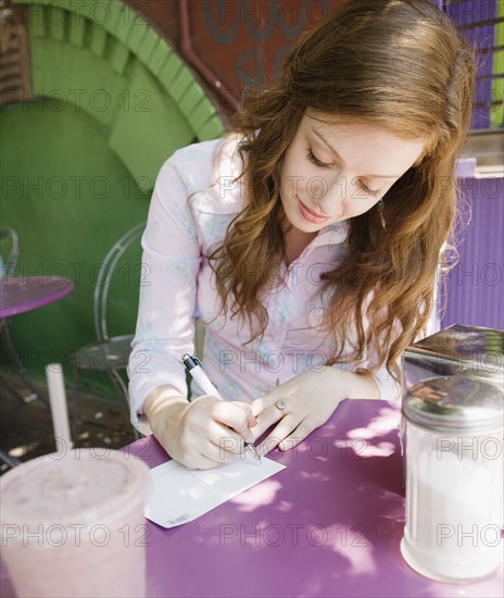 Woman writing note in outdoor cafe. Date : 2008