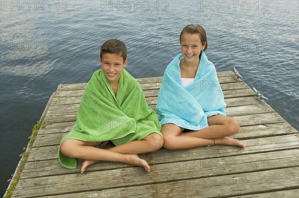 Children wrapped in towels on dock.