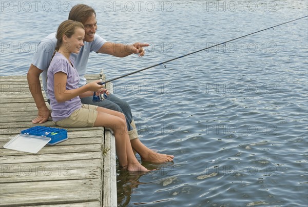 Father and daughter fishing off dock.