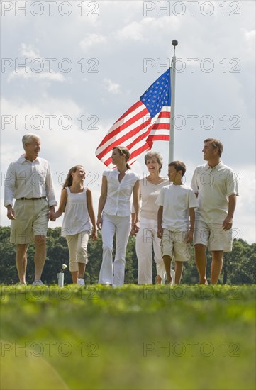Multi-generational family walking in front of American flag.