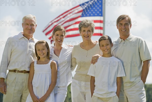 Multi-generational family posing in front of American flag.