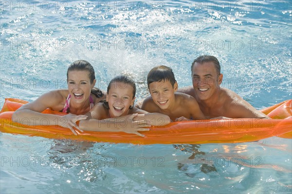 Family resting on raft in swimming pool.