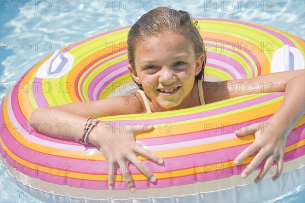 Girl playing in inflatable tube in swimming pool. Date : 2008